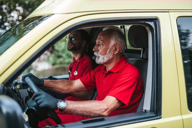 Photo emergency medical service male workers driving in ambulance car.