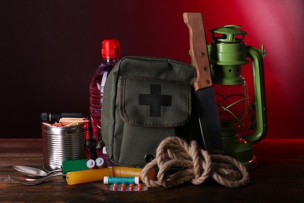 Emergency preparation equipment on wooden table on dark background