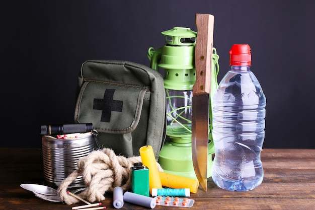 Emergency preparation equipment on wooden table on dark background