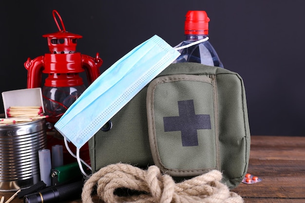 Emergency preparation equipment on wooden table on dark background