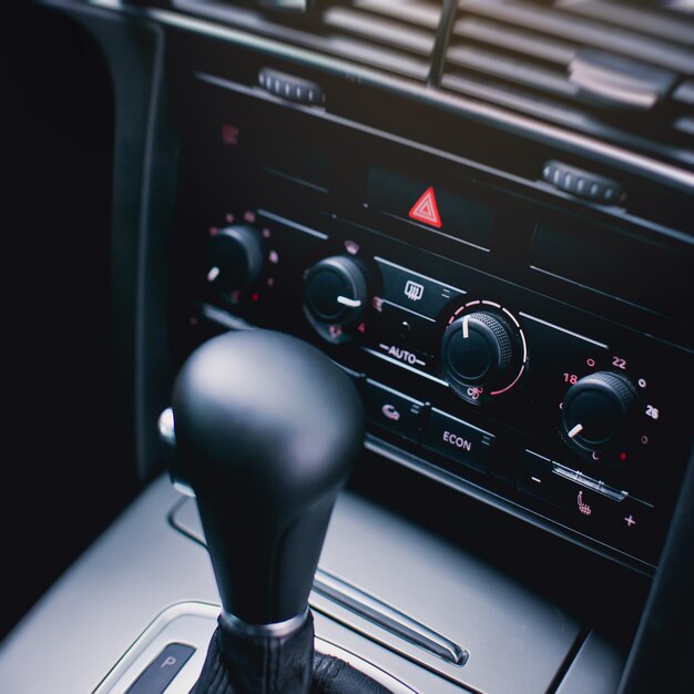 Emergency stop button with red tiangle sign and climate control panel in modern luxury car interior details