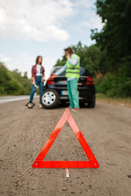 Emergency stop sign, car breakdown, couple calling for tow truck.