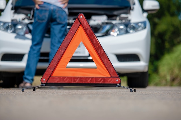 Emergency stop sign and driver near broken car on road. 