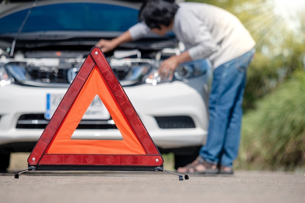 Emergency stop sign and driver near broken car on road. 