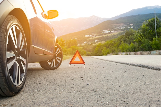 An emergency stop sign of a vehicle is installed on the road, next to the car. Copy space.