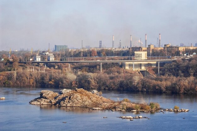 Emission of smoke from pipes of a metallurgical plant. The problem of air pollution and global warming. Environmental protection concept. Zaporozhye, Ukraine. View of the Dnieper river