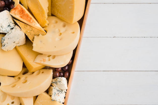 Photo emmental; blue; cheddar cheese with olives in tray on white desk