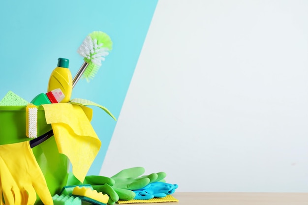 Emmer met schoonmaakspullen en gereedschap op tafel in de buurt van kleurenmuur