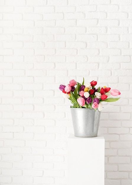 Emmer verse tulp bloemen op witte bakstenen muur achtergrond