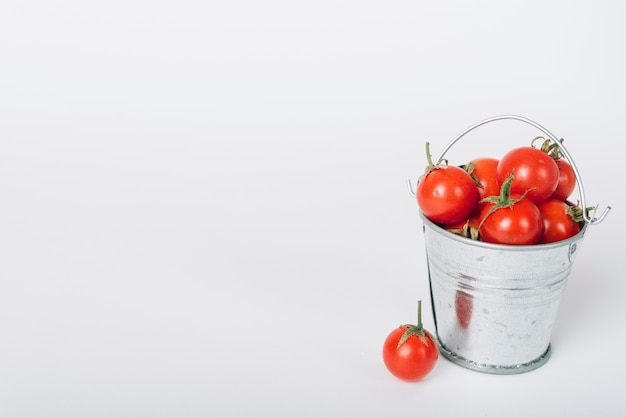 Foto emmer vol met rode sappige tomaten op witte achtergrond