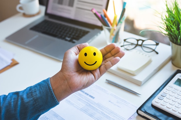 Emoticon bal op mannenhand op werktafel gelukkig leven concepten inspiratie en motivatie idee