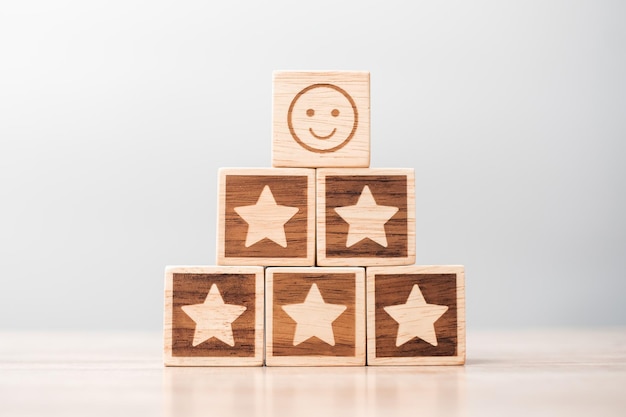 Emotie gezicht en ster symbool blokken op tafel achtergrond Service rating ranking klant beoordeling tevredenheid evaluatie en feedback concept