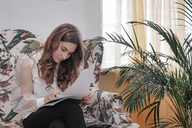 Emotie jonge vrouw zit in de wachtkamer en vult arbeidspapieren in. Vrouw zittend op de bank en vragenlijst op papier schrijven. Begrip werkgelegenheid. Selectieve aandacht. Ruimte kopiëren