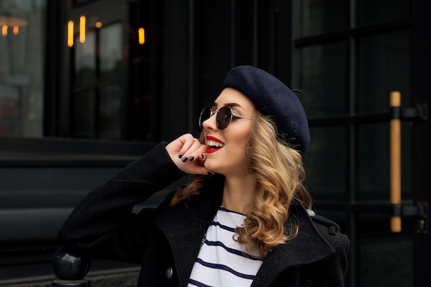 Emoties, mensen, schoonheid en lifestyle concept - Girl Frenchwoman. Straatfoto van een jonge vrouw die stijlvolle klassieke kleding draagt. Vrouwelijk modeconcept. Franse stijl.