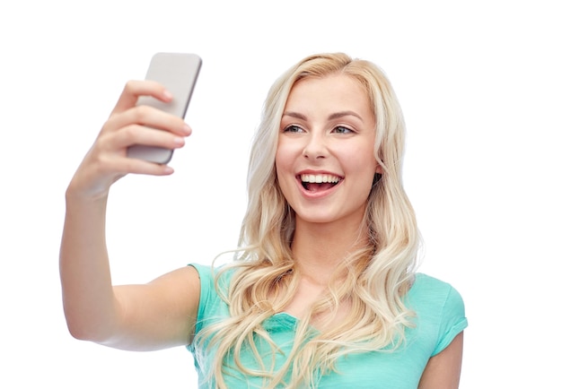 emoties, uitdrukkingen en mensenconcept - gelukkige glimlachende jonge vrouw of tienermeisje die selfie met smartphone nemen