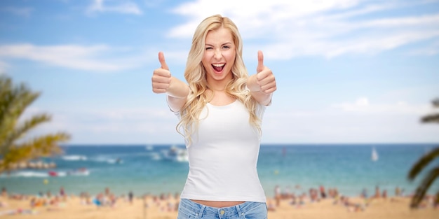emoties, zomervakantie, reizen, reclame en mensenconcept - gelukkig lachende jonge vrouw in wit t-shirt duimen opdagen over exotisch tropisch strand met palmbomen en zee achtergrond