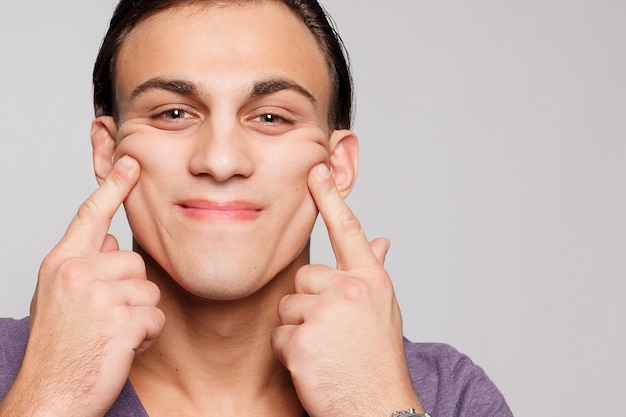 Emotion, advertisement and people concept - Handsome young man on grey background looking at camera. Portrait of sexy man. Happy guy smiling.