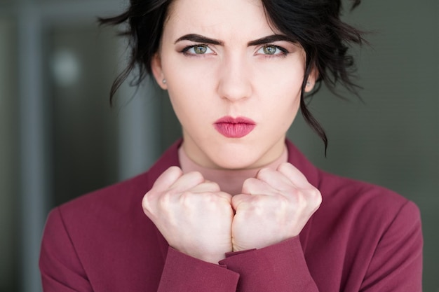 Emotion face angry mad cross woman clenching fists fury and rage concept young beautiful brunette girl portrait