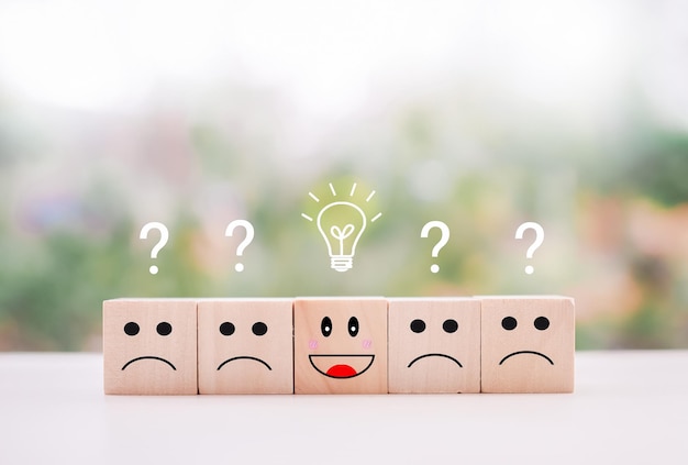 Emotion face wooden block with light bulb and question mark for leadership creative idea innovation concept