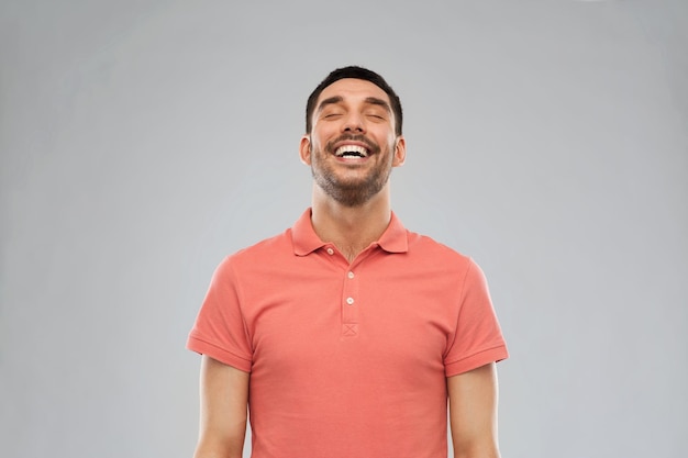 emotion and people concept - laughing man in polo t-shirt over gray background