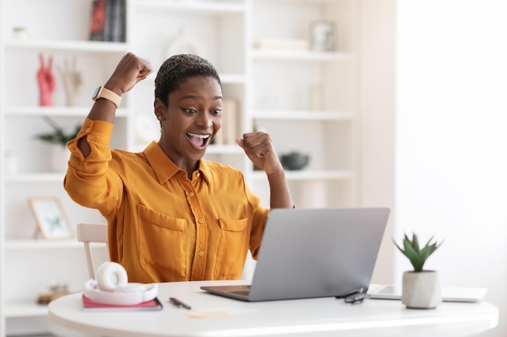 Photo emotional african american businesswoman celebrating success working on laptop