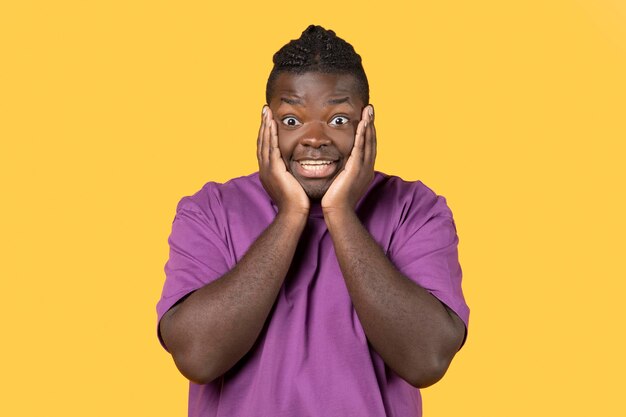 Emotional african american guy looking with amazement on yellow background