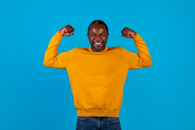 Emotional african american man celebrating success on blue