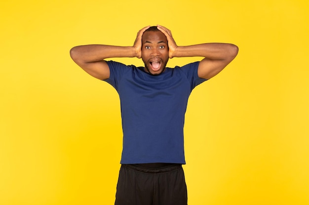 Emotivo sportivo afroamericano che grida in posa su sfondo giallo