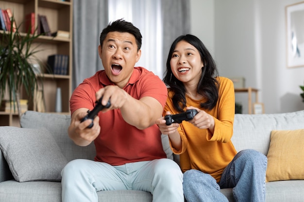 집에서 비디오 게임을 하는 감정적인 아시아 커플