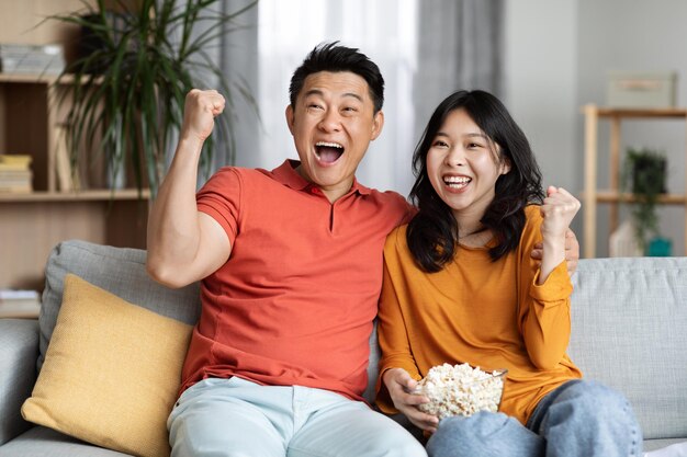 집에서 TV 쇼를 보는 감정적인 아시아 남자와 여자