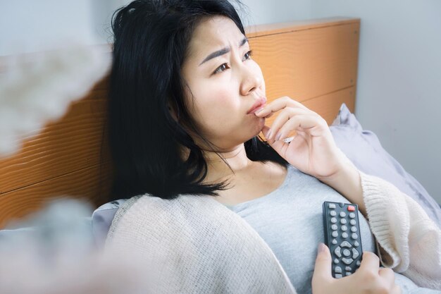 Emotional asian woman watching sad movie on tv