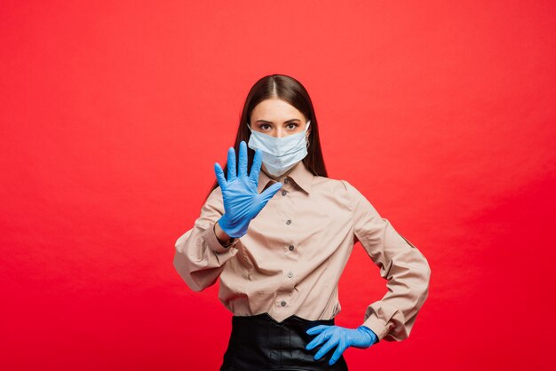 Emotional beautiful businesswoman in medical mask and gloves making stop gesture