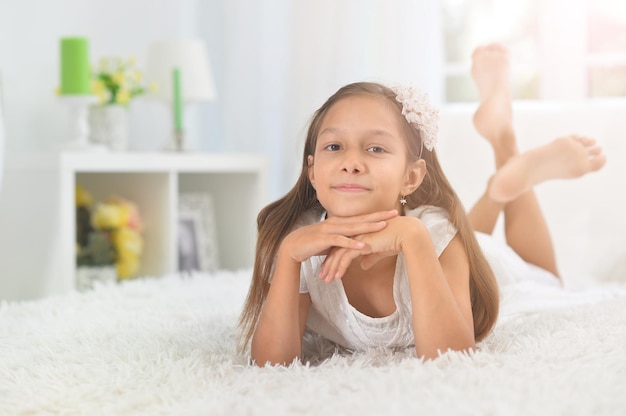 Emotional beautiful little girl posing at home on bed