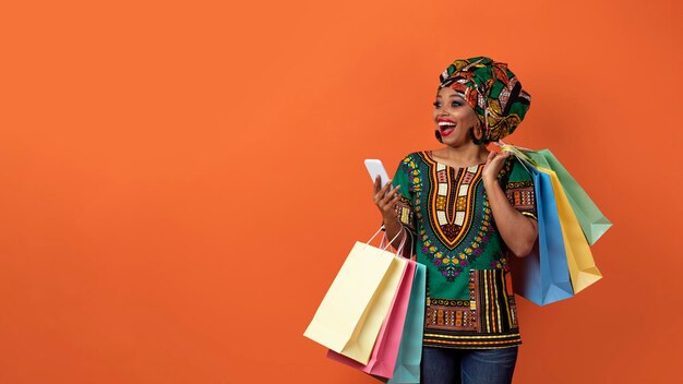 Photo emotional black woman in african costume shopping online copy space