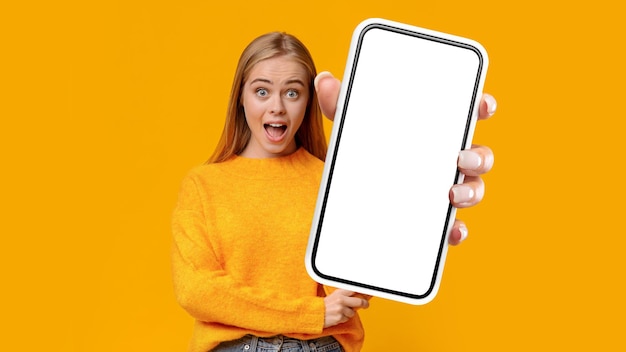 Emotional blonde lady showing mobile phone with blank screen