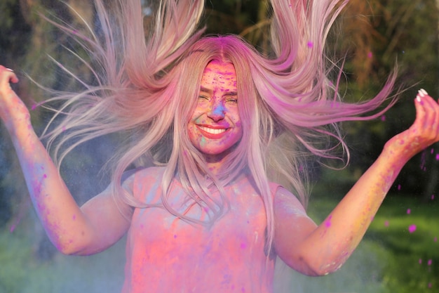 Foto modello biondo emotivo con capelli svolazzanti in posa ricoperti di una vernice colorata all'holi festival