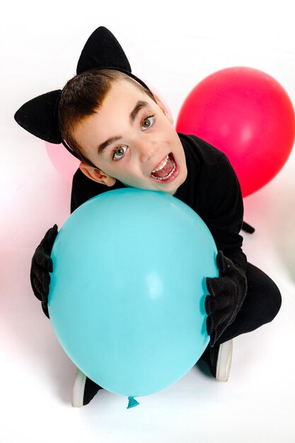 Emotional boy dressed as a black cat with a blue balloon Isolated Purim Halloween