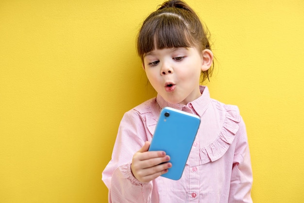 Emotional child girl talking on phone online translation sharing news with friend expressing surpris