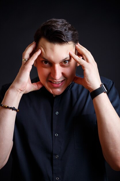 Emotional close-up portrait of a young male doctor in medical clothes. Isolated on black background