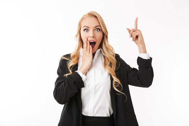 Emotional excited business woman posing isolated over white wall pointing.