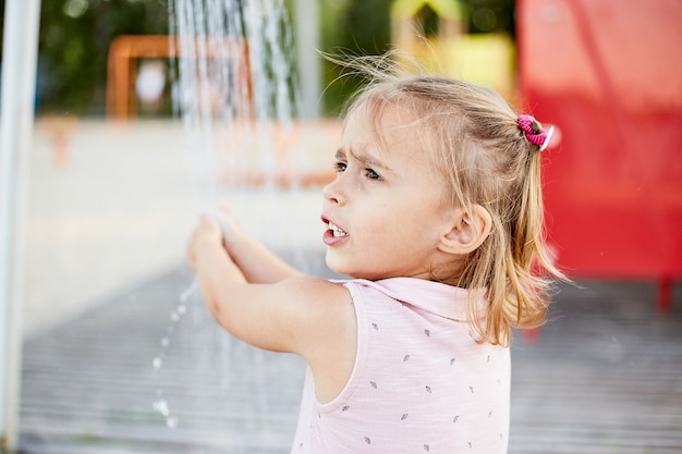 Emotional funny girl playing with beach shower