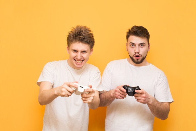 Photo emotional gamers with gamepad in hand, playing video games focused on yellow