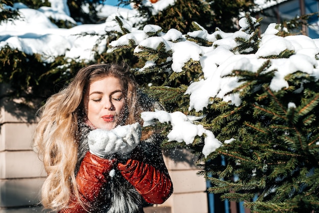 Emotional girl blowing snow in her hands