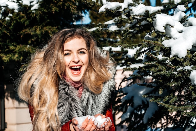 Emotional girl blowing snow in her hands