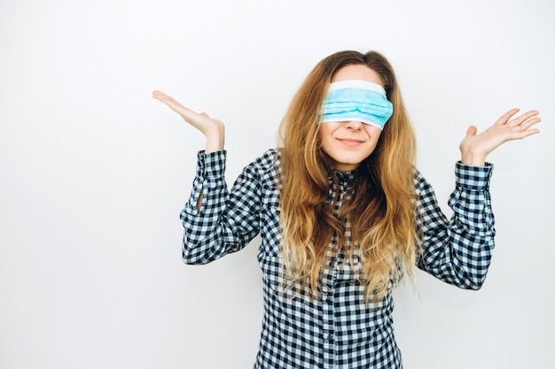 An emotional girl in a medical mask on a white wall. how to protect against coronavirus? Girl in a panic because of COVID 2019.