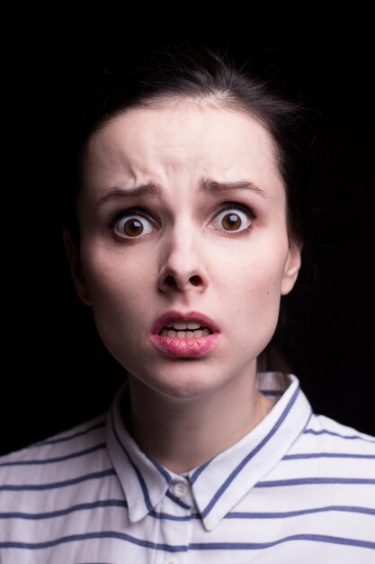 emotional girl in a striped shirt on a black background