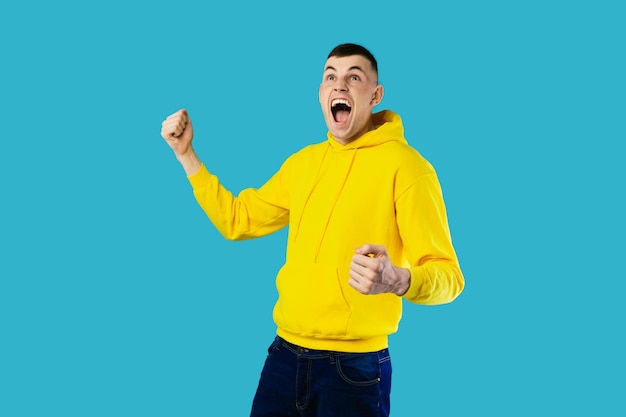 Emotional guy shouting gesturing yes celebrating victory blue background