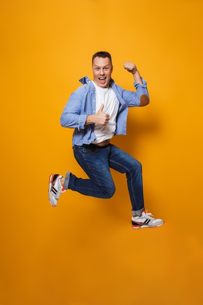 Emotional happy man jumping make thumbs up gesture.