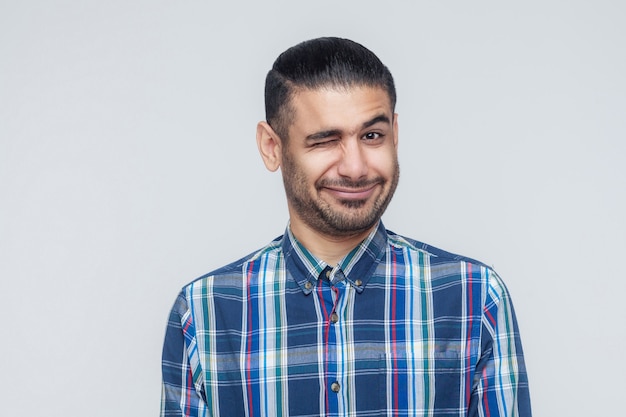 Photo emotional hipster man wink and smiling at camera. good humans emotions and feelings. studio shot, gray wall