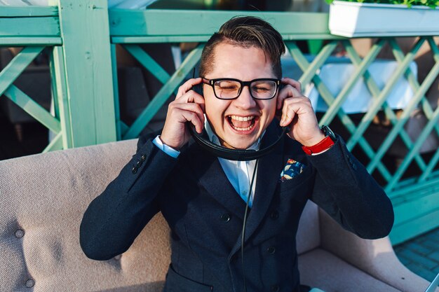 Emotional joyful young man listening to music on headphones and having fun